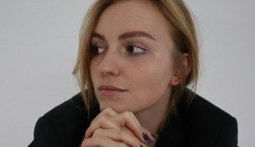 a-woman-in-a-black-jacket-is-sitting-down.jpg a woman in a black jacket is sitting down
